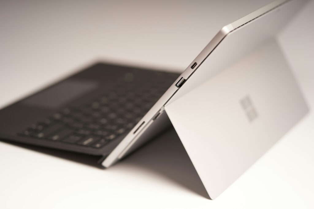 Zijaanzicht van een Microsoft Surface-tablet met toetsenbordcover en uitklapbare standaard, waarbij de USB- en USB-C-poorten zichtbaar zijn.