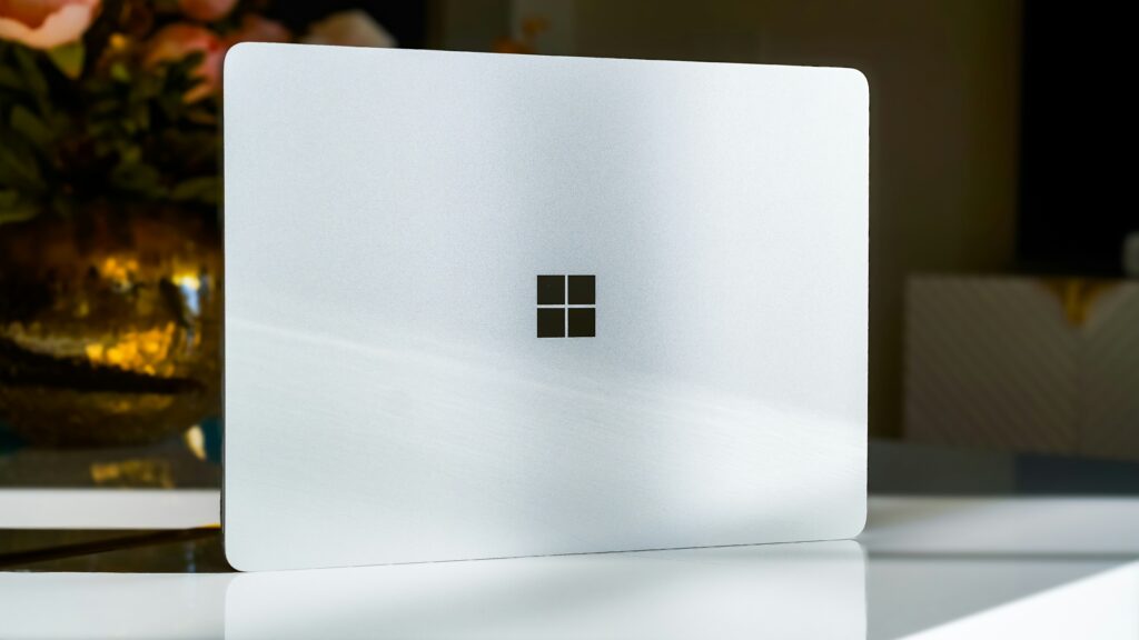 Minimalistisch ontwerp van een Microsoft Surface laptop op een modern bureau, met het herkenbare Microsoft-logo in beeld.